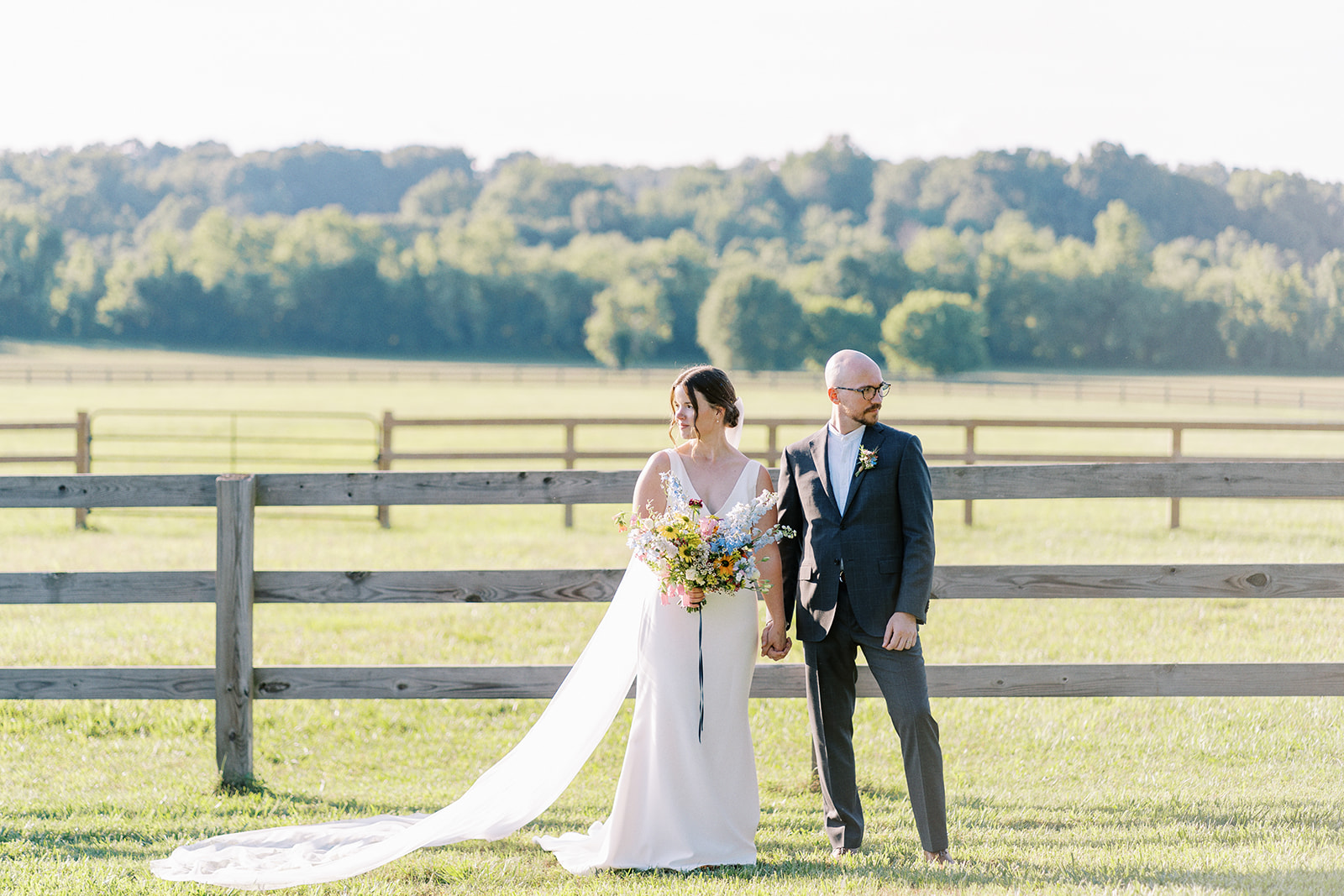 Couple stand with miles of horse farm behind them on their wedding day