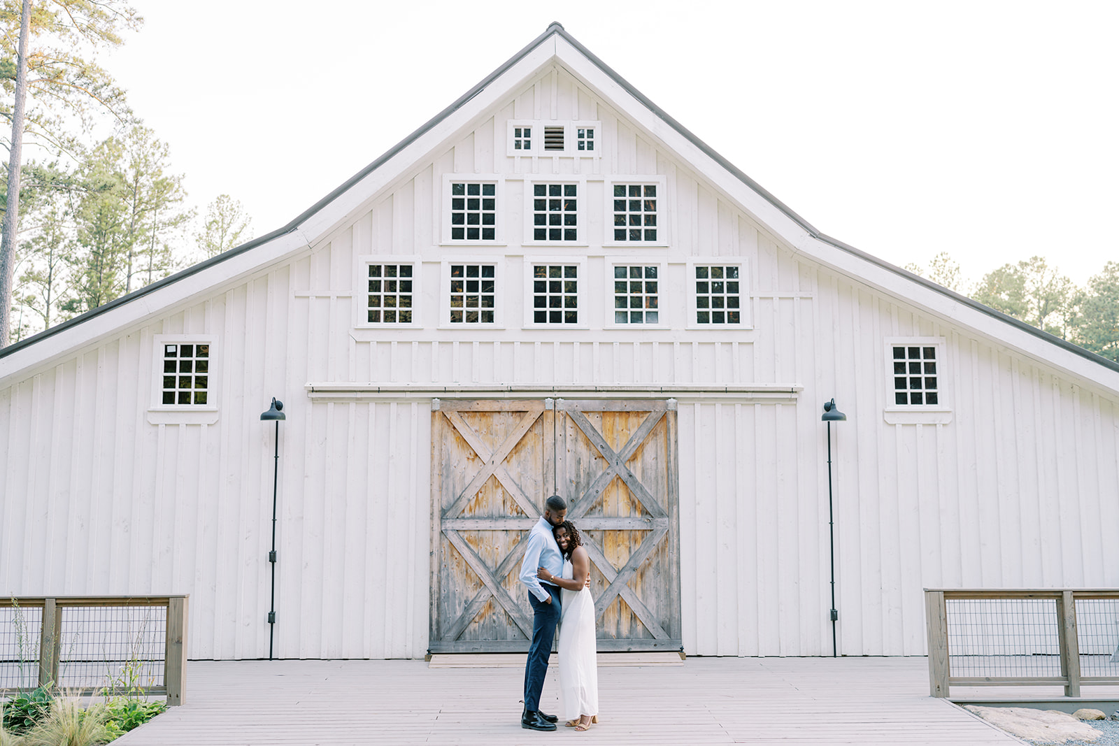 Agnes and Uzo share a tender embrace beside the rustic barn at Union Grove Barn in Chapel Hill, North Carolina, captured by North Carolina wedding photographer Jessica Leigh Mason.