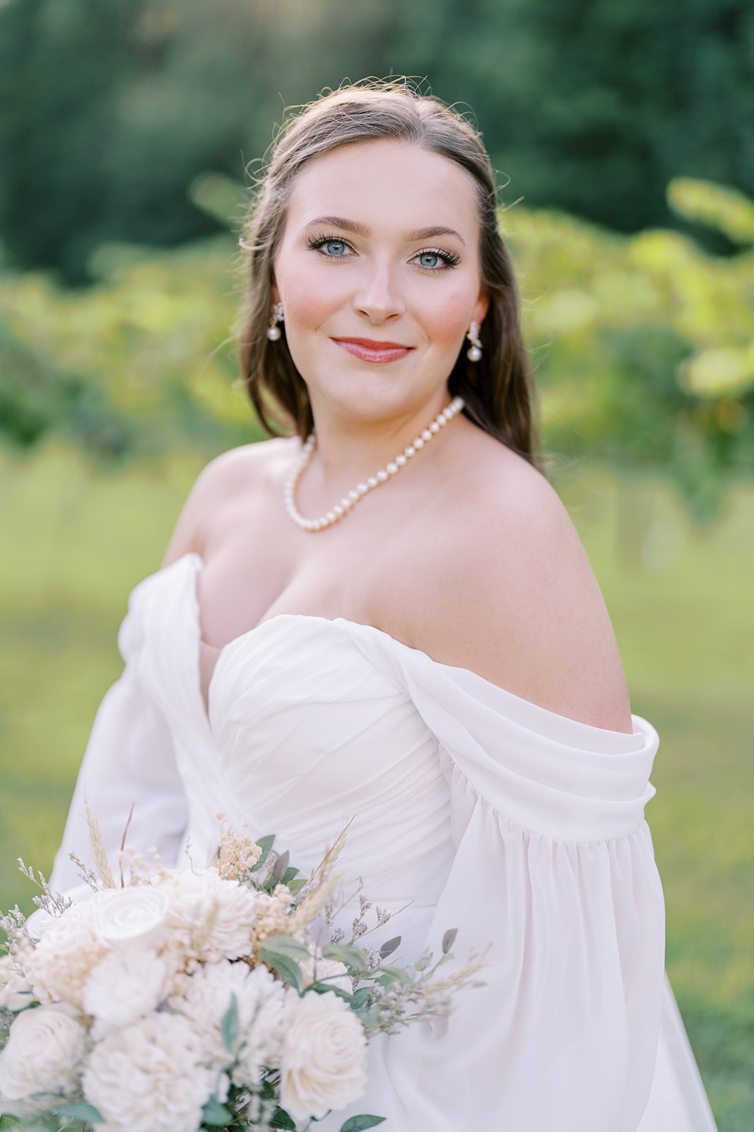 A close-up film photo of the bride with soft, glowing light, natural makeup, and a romantic off-shoulder dress during her session at The Vines of Lexington in South Carolina, captured by Durham wedding photographer Jessica Leigh Mason.