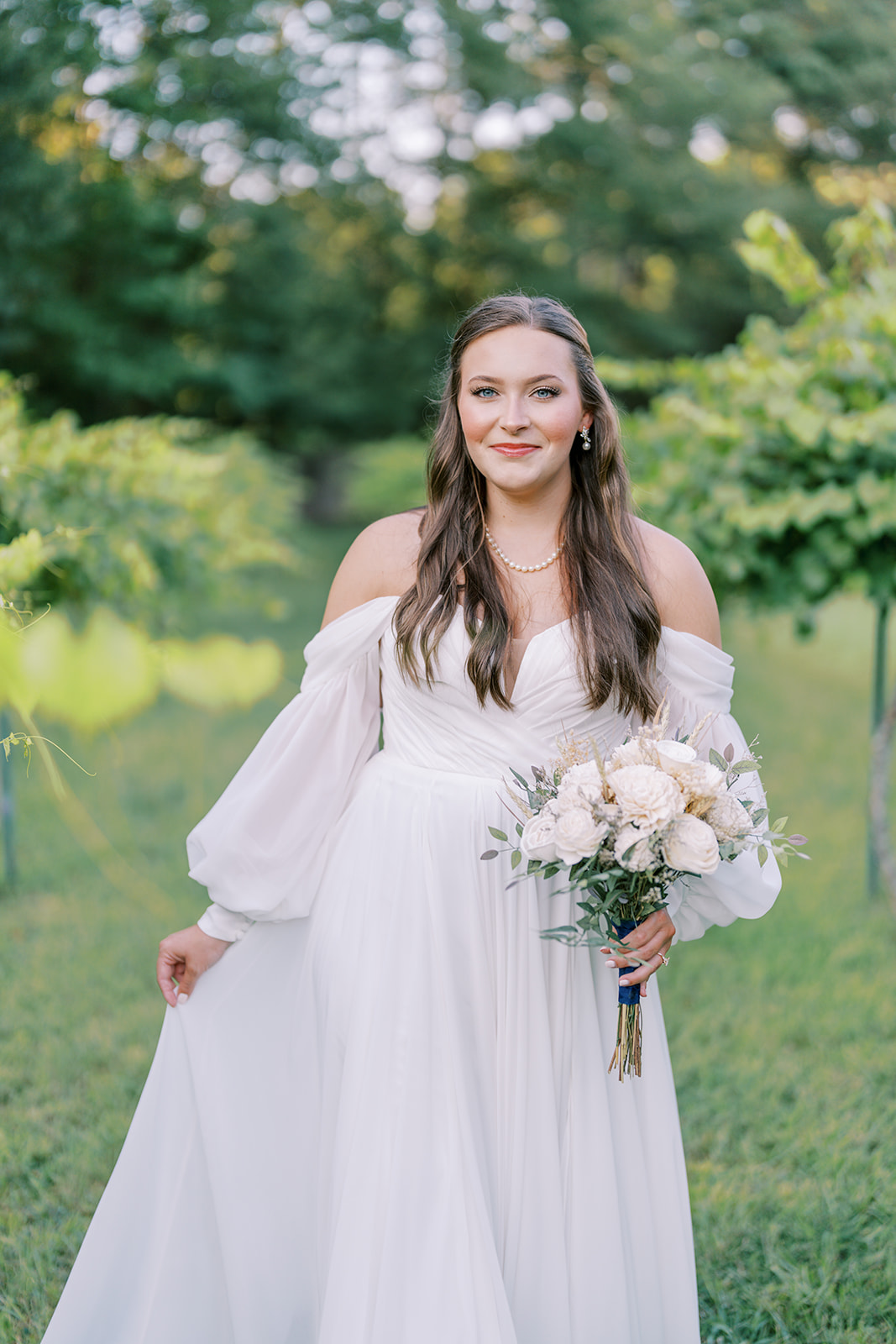 A close-up of Cameron walking through The Vines of Lexington wedding venue in South Carolina, her flowy off-shoulder dress trailing beautifully behind her, captured by Durham wedding photographer Jessica Leigh Mason.
