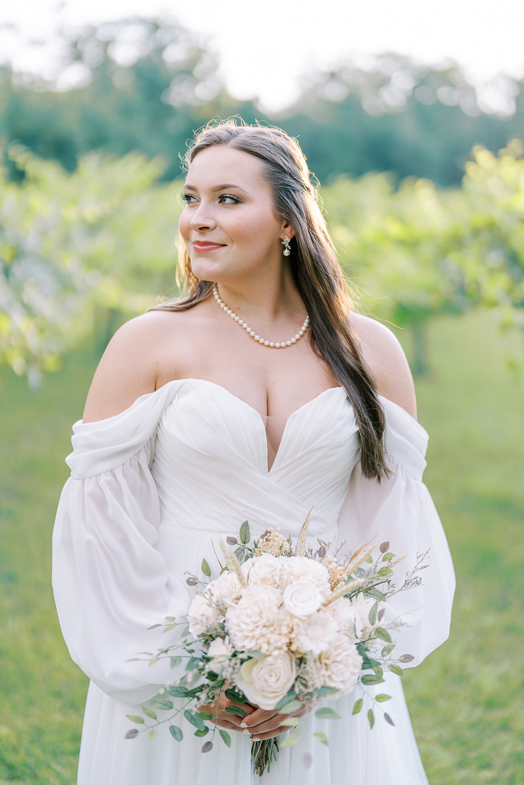 A close-up of Cameron wearing heirloom pearls and a romantic off-shoulder wedding dress during her bridal session at The Vines of Lexington in South Carolina, captured by Durham wedding photographer Jessica Leigh Mason.