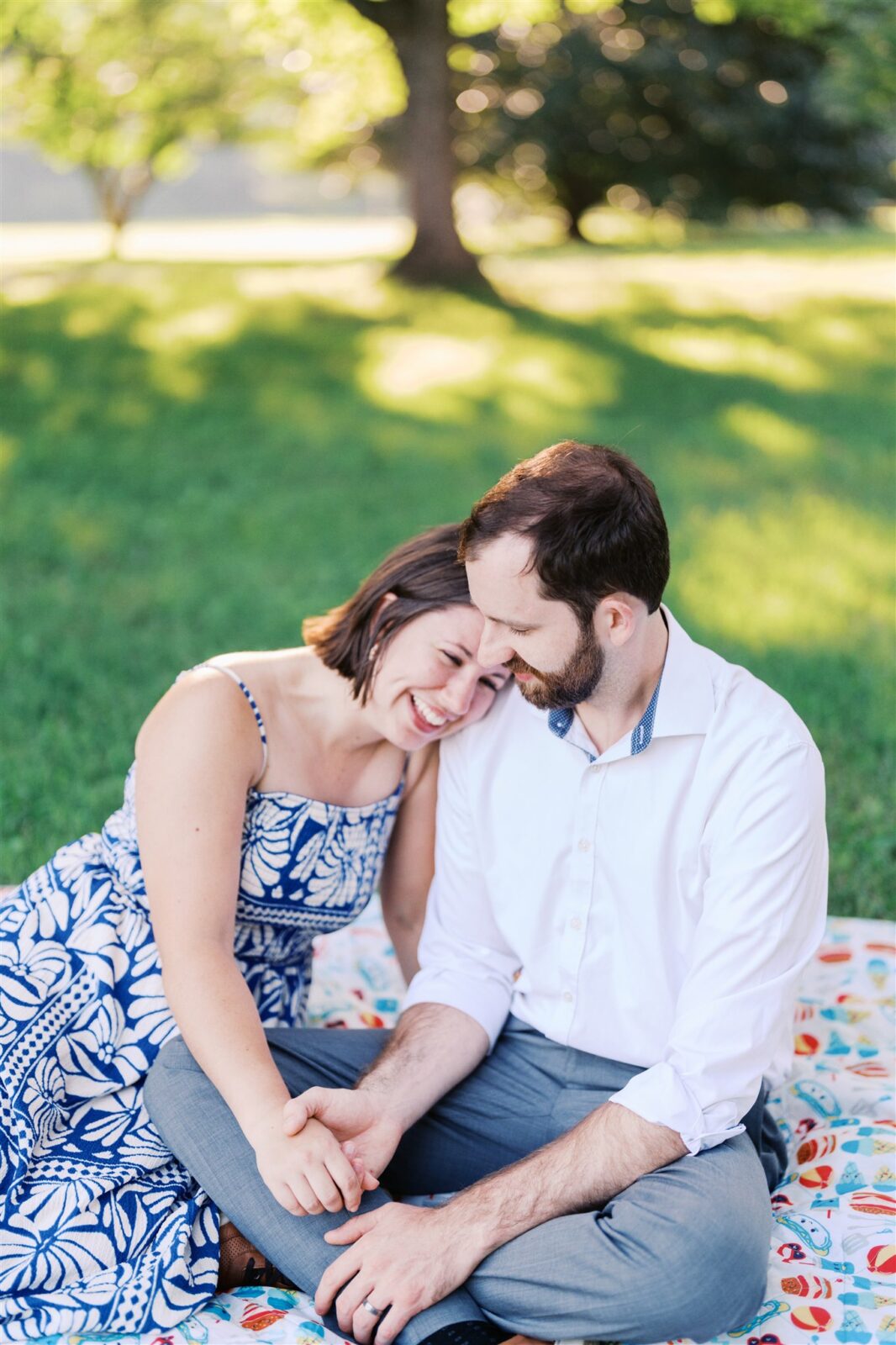 Katie and Sam laughing while holding hands during their anniversary photo session at Ayr Mount in Hillsborough NC, capturing their playful and joyful connection.