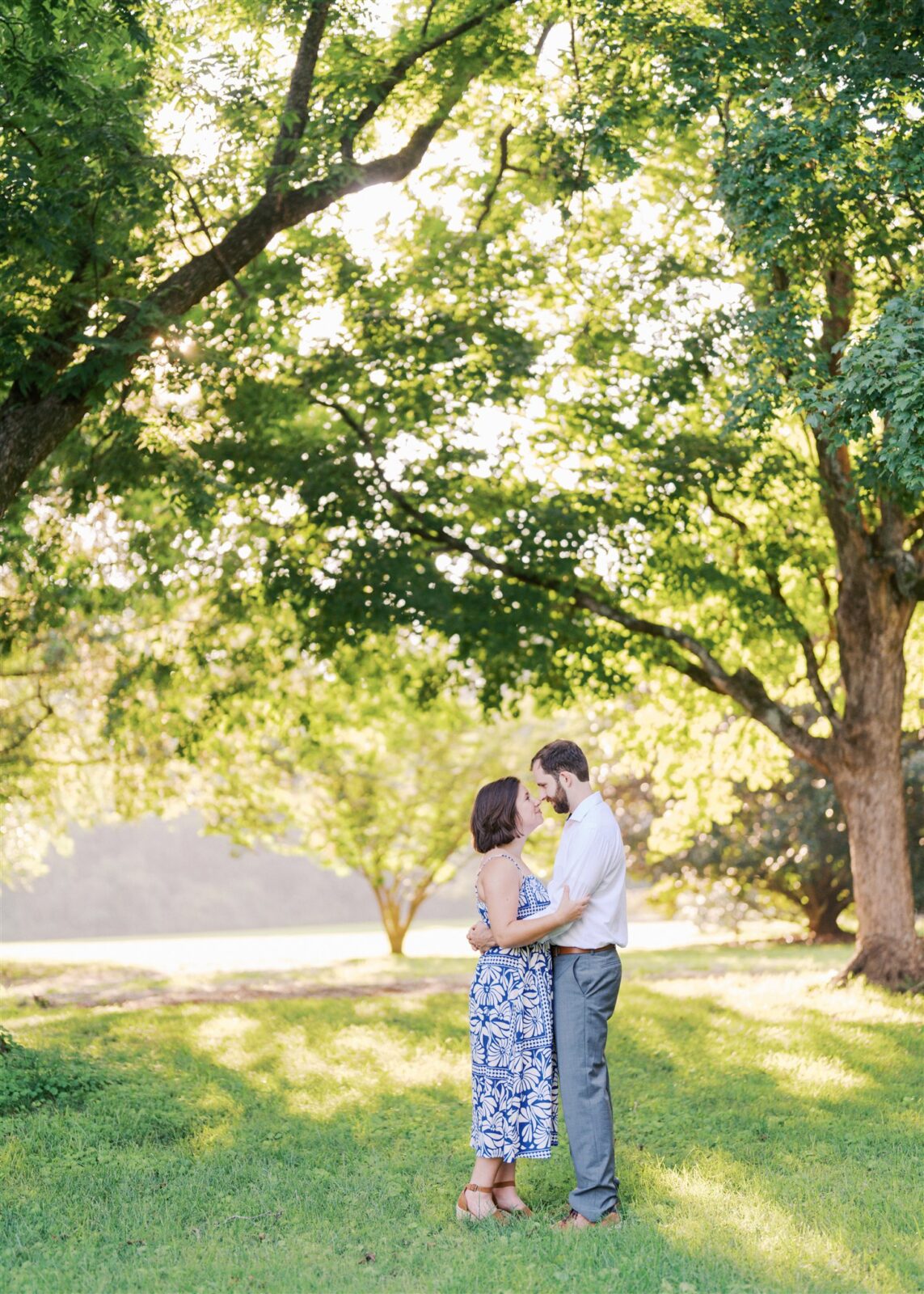 Katie and Sam standing nose to nose under a beautiful tree canopy at Ayr Mount in Hillsborough NC during their anniversary photo session.