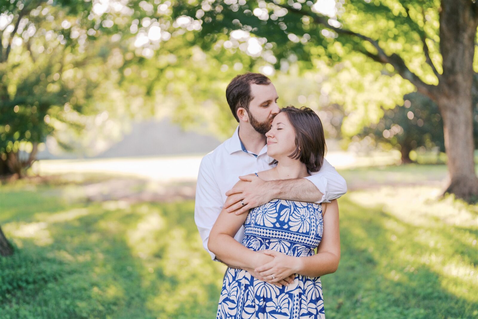 Sam kissing Katie’s forehead in a scenic landscape at Ayr Mount in Hillsborough NC during their anniversary photo session.