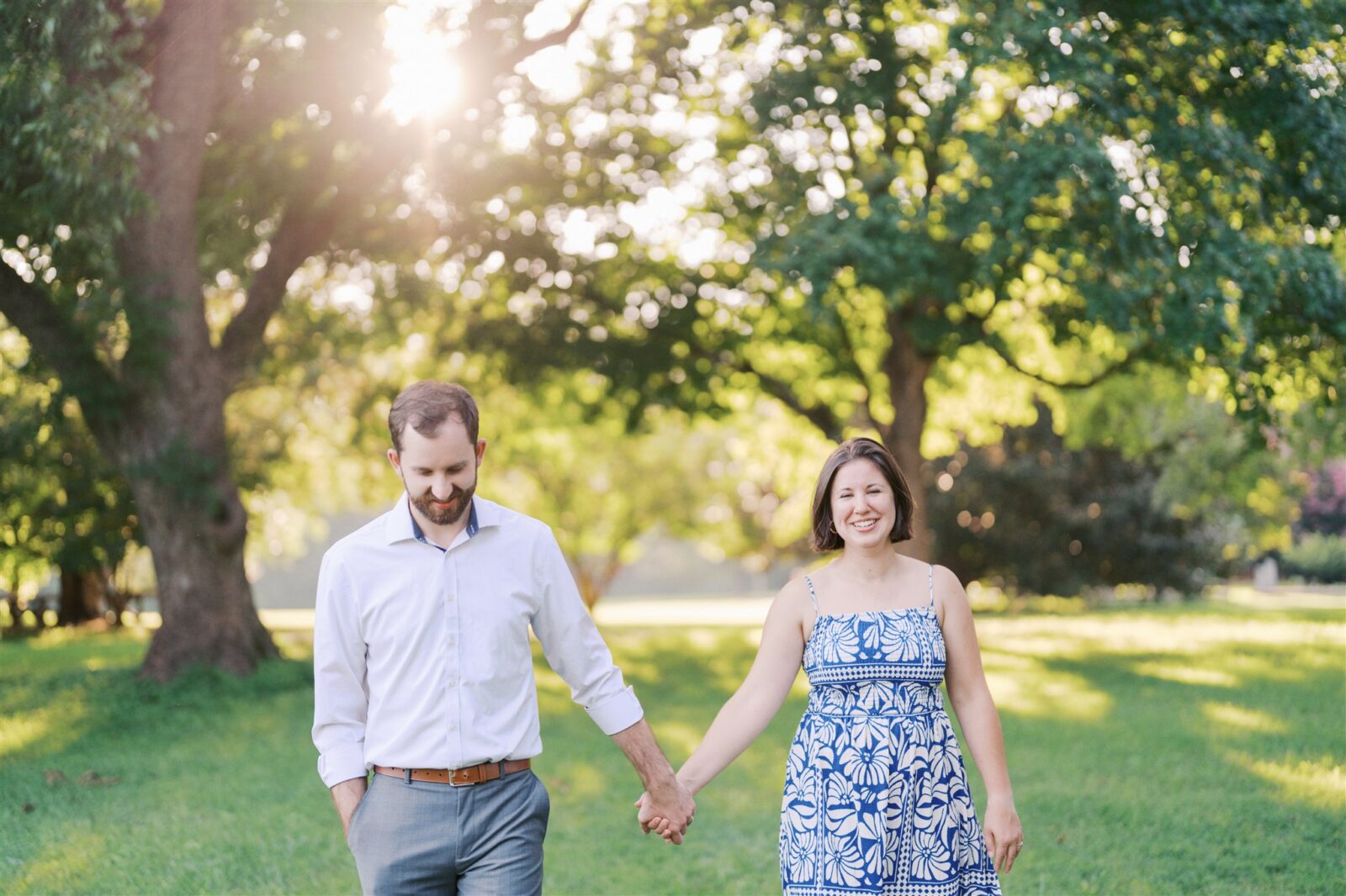 Katie and Sam walking hand in hand through the scenic landscape at Ayr Mount in Hillsborough NC during their anniversary photo session.