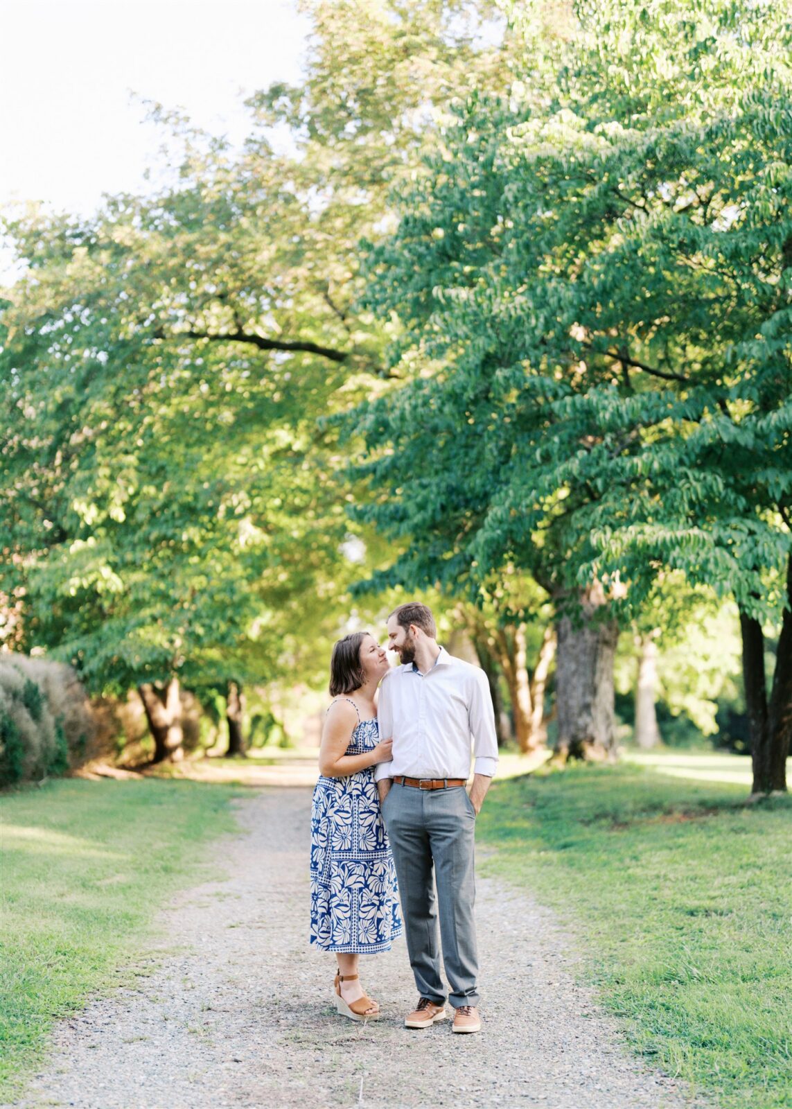 Katie and Sam standing nose to nose on a beautiful dirt path at Ayr Mount in Hillsborough NC during their anniversary photo session, capturing a tender and romantic moment.