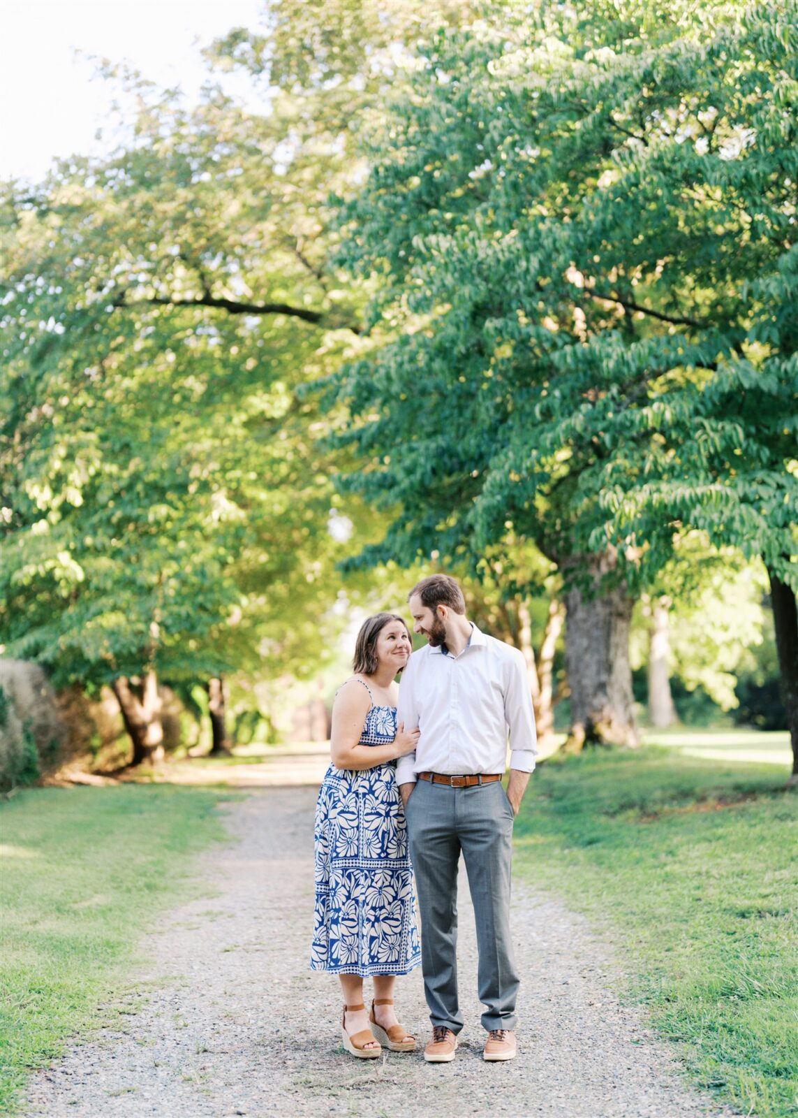 Katie and Sam snuggling together on a dirt path at Ayr Mount in Hillsborough NC during their anniversary photo session.