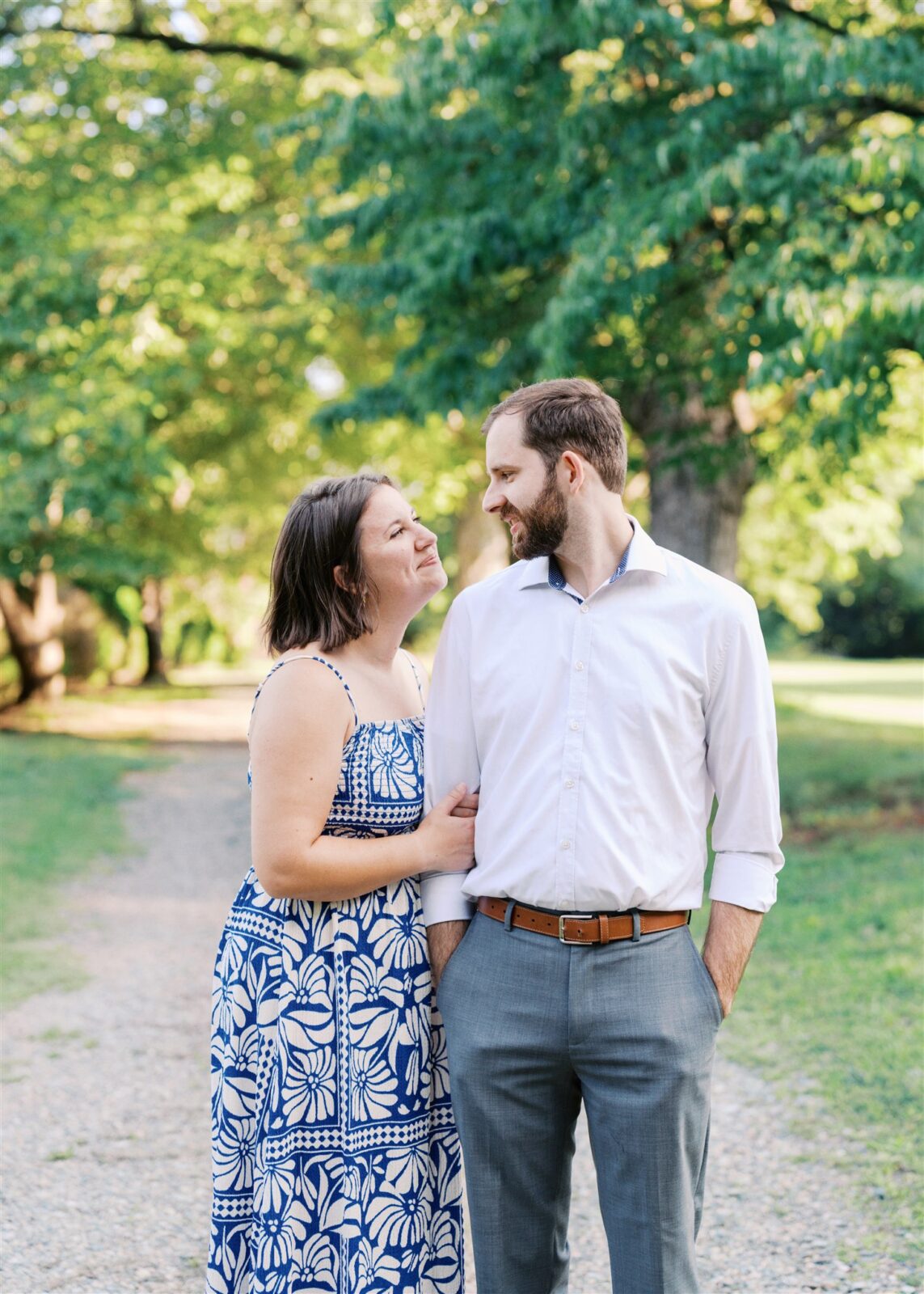 Katie looking at Sam while holding his arm during their anniversary photo session at Ayr Mount in Hillsborough NC, capturing a tender and joyful moment.