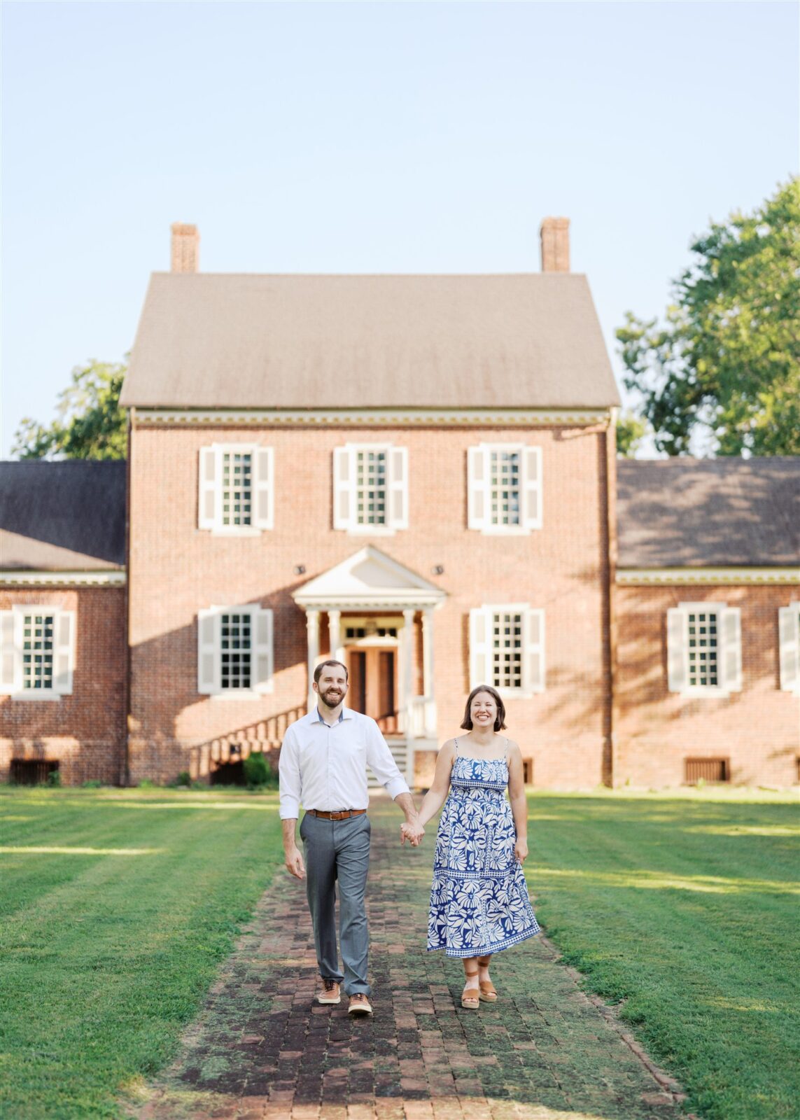 Katie and Sam walking together with the front of the historic Ayr Mount house in the background during their anniversary photo session in Hillsborough NC.