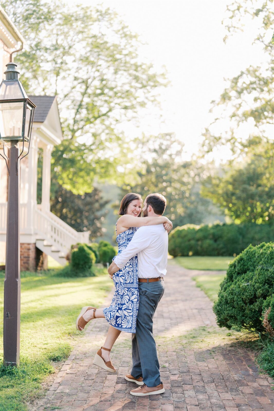Sam lifting and spinning Katie during their anniversary photo session at Ayr Mount in Hillsborough NC, capturing a playful and romantic moment.
