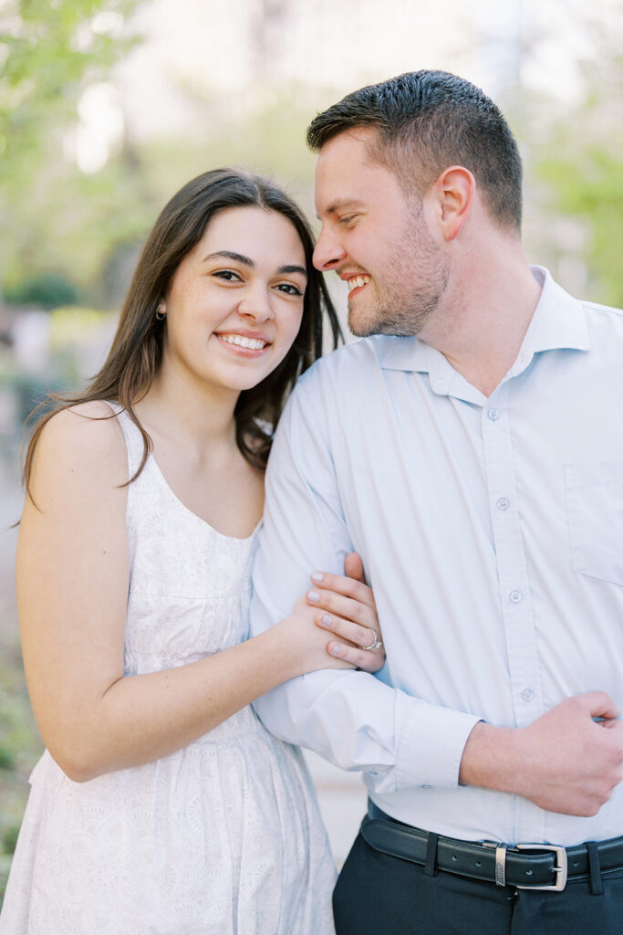 Engaged couple sharing a portrait under blooming cherry blossoms at Romare Bearden Park in Charlotte, North Carolina during their spring engagement session