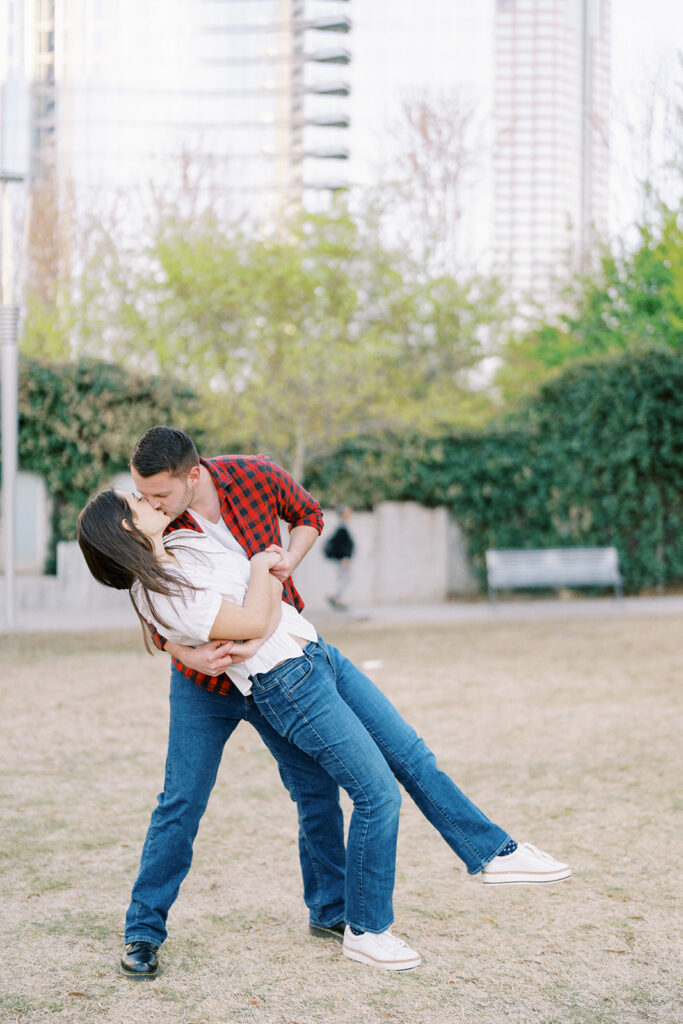 Romantic dip and kiss between Rachel and Nate during their engagement session in uptown Charlotte