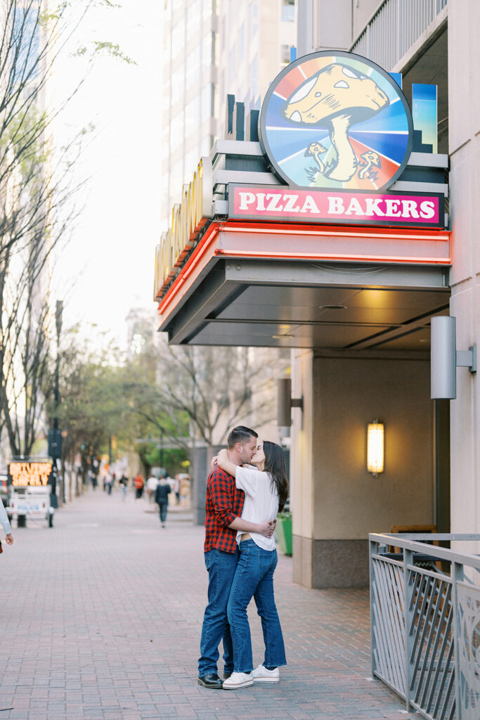 Couple sharing a kiss on the streets of uptown Charlotte during their engagement session