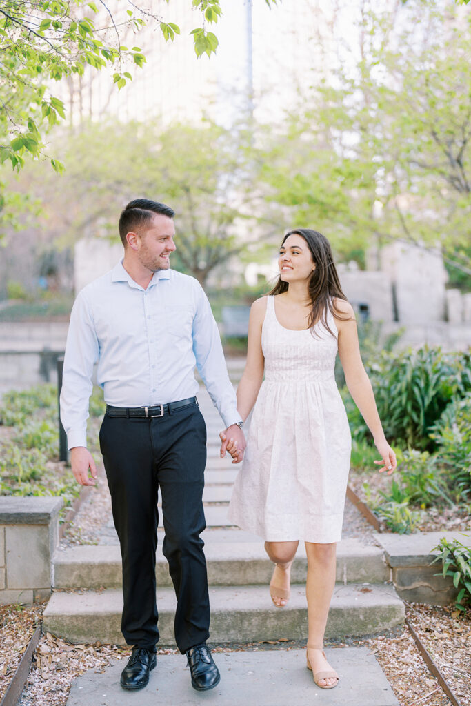 Rachel and Nate strolling along the pathways of Romare Bearden Park surrounded by spring flowers