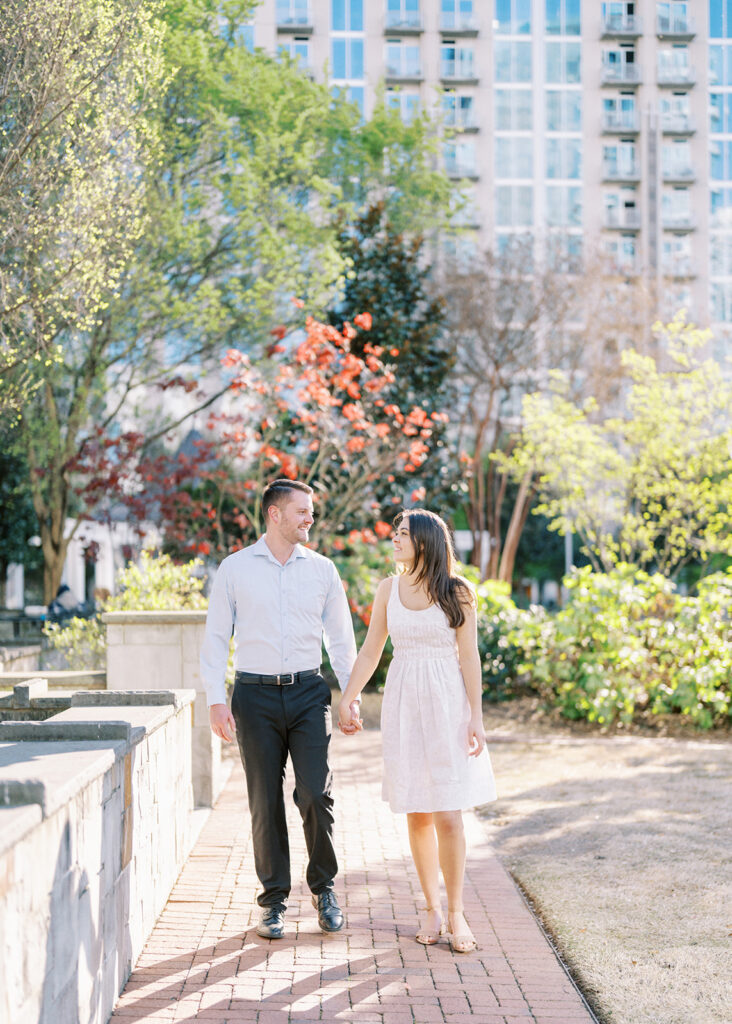 Rachel and Nate walking hand-in-hand through uptown Charlotte during their engagement session
