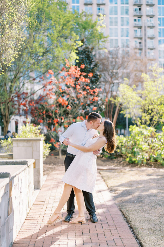 Couple sharing a romantic dip and kiss in uptown Charlotte during a spring engagement session