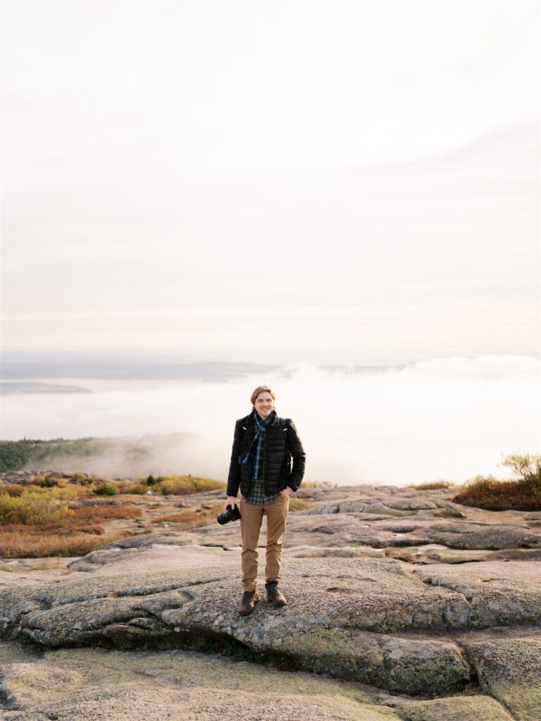 Figure standing in the mist as fog rolls over Cadillac Mountain in Acadia Maine
