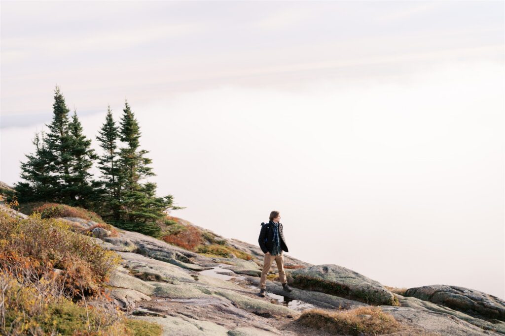 Figure looking out into the clouds and mist from Cadillac Mountain in Acadia Maine
