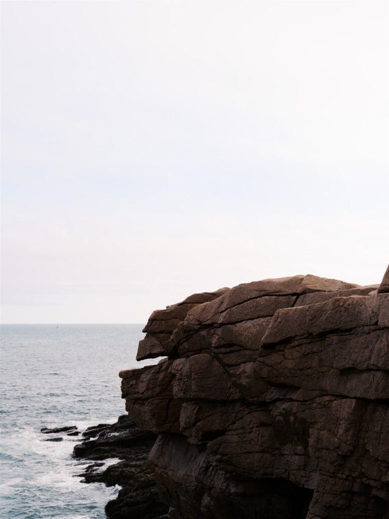 Minimalist coastal cliff with vast water and sky backdrop along the Maine coast in Acadia
