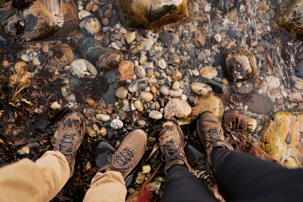 Feet resting on the colorful rounded pebbles at Little Hunters Beach in Acadia Maine
