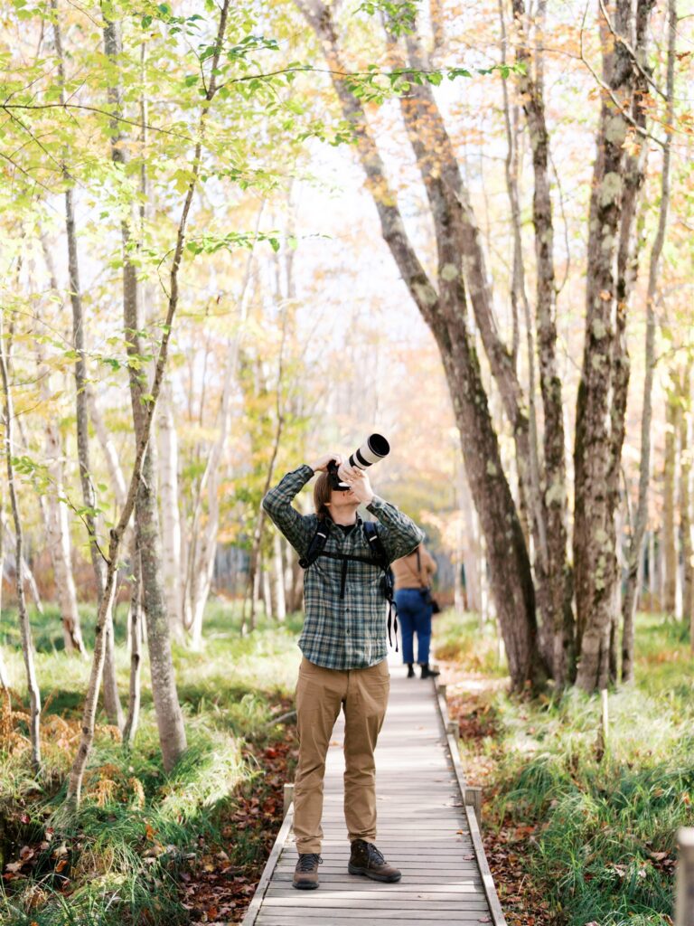 Photographer capturing nature details along the Jessup Trail boardwalk in Acadia Maine