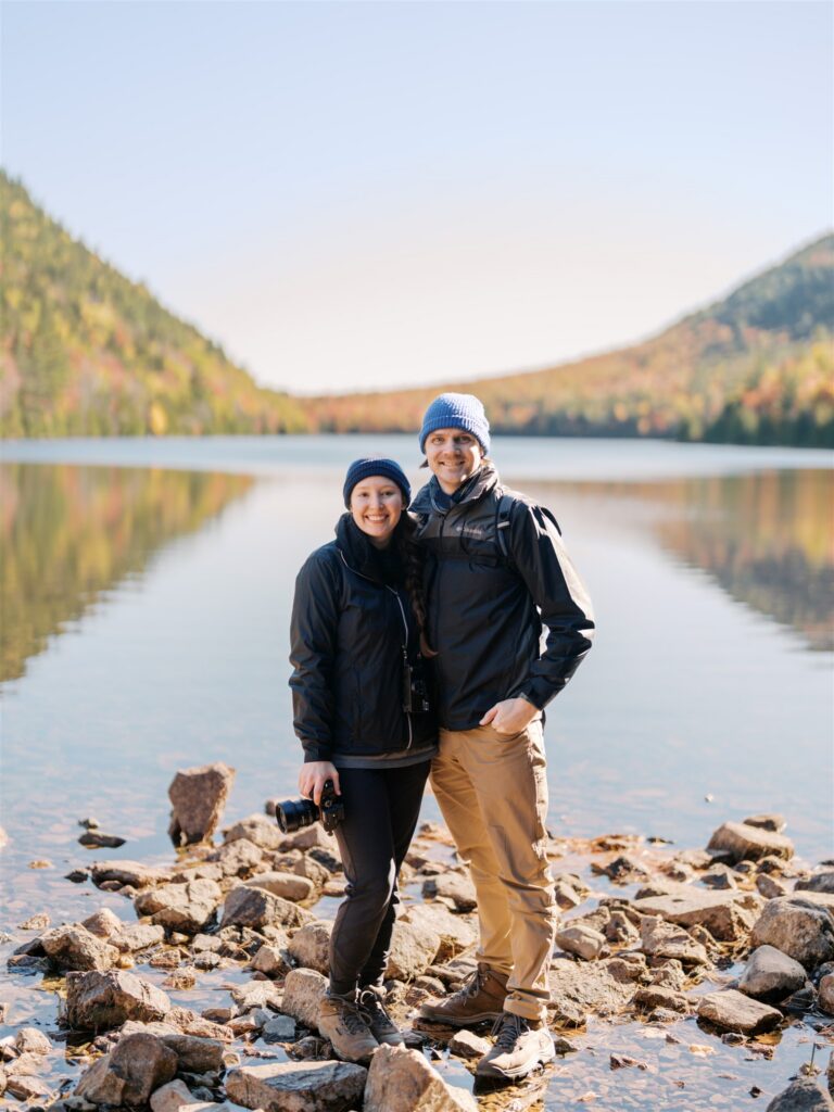 Couple posing for an engagement session surrounded by fall foliage in Acadia National Park Maine

