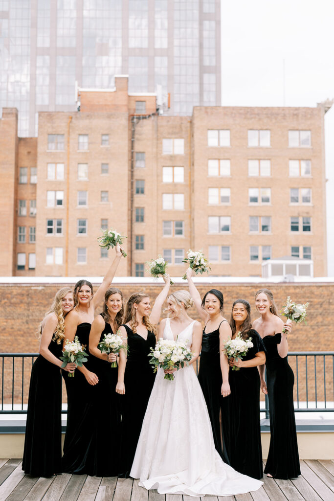 Bride with bridesmaids sharing a joyful moment overlooking the Raleigh skyline