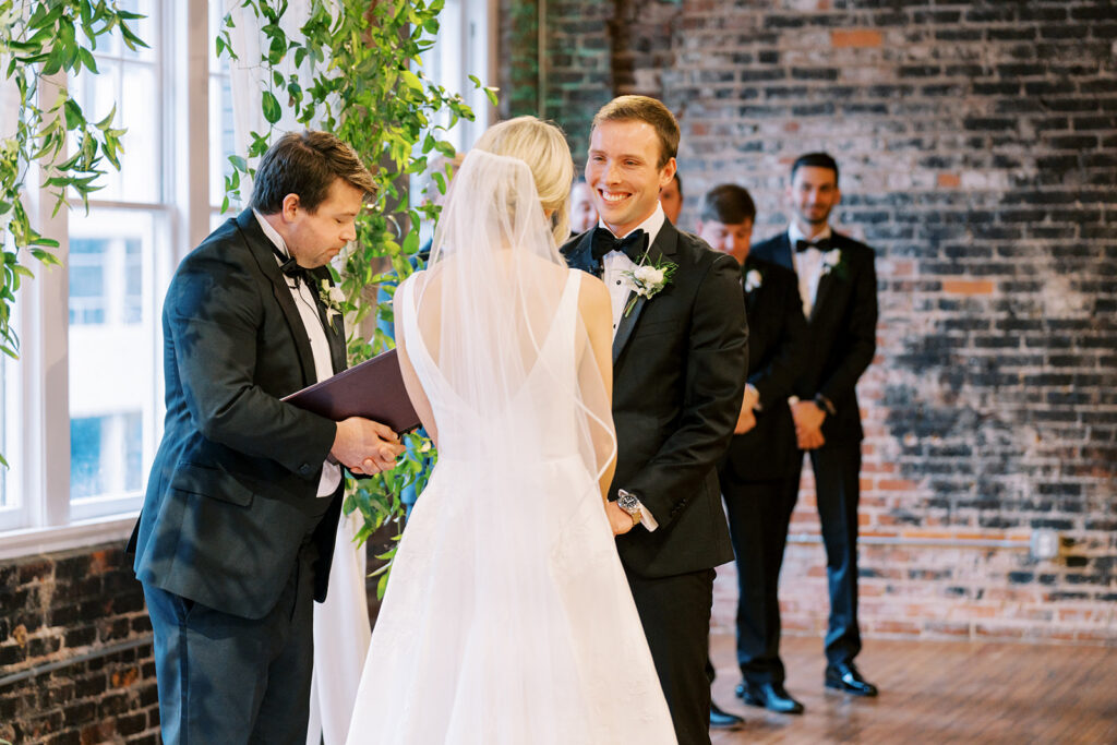 Couple holding hands at the altar while speaking their vows during an indoor ceremony