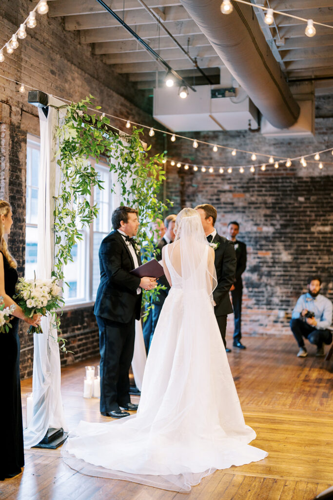 Wedding ceremony scene with bride and groom facing each other at the altar