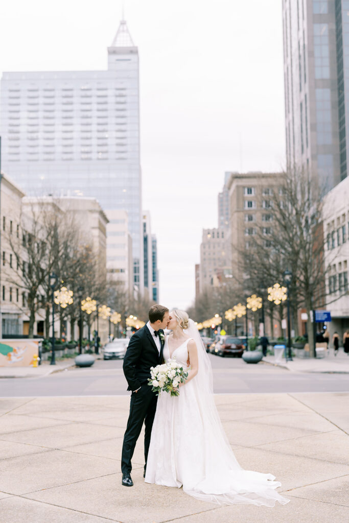 Newlyweds posing with the Raleigh skyline after a winter wedding at Stockroom 230