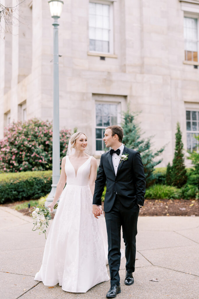 Bride and groom walking hand in hand during their wedding day in downtown Raleigh