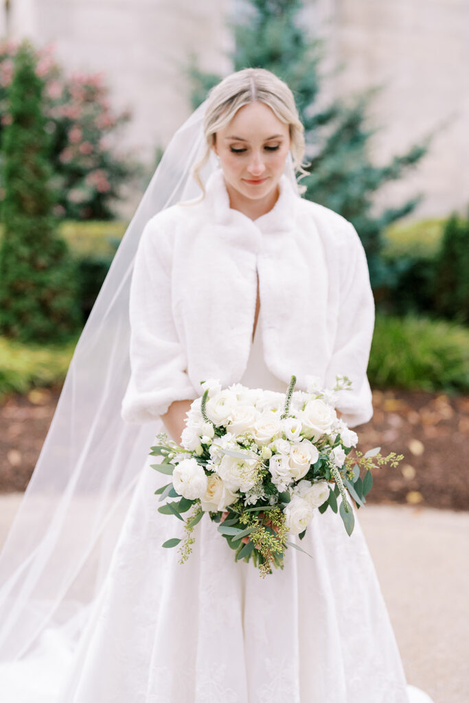 Bride wrapped in a winter shawl holding her bridal bouquet during an outdoor portrait