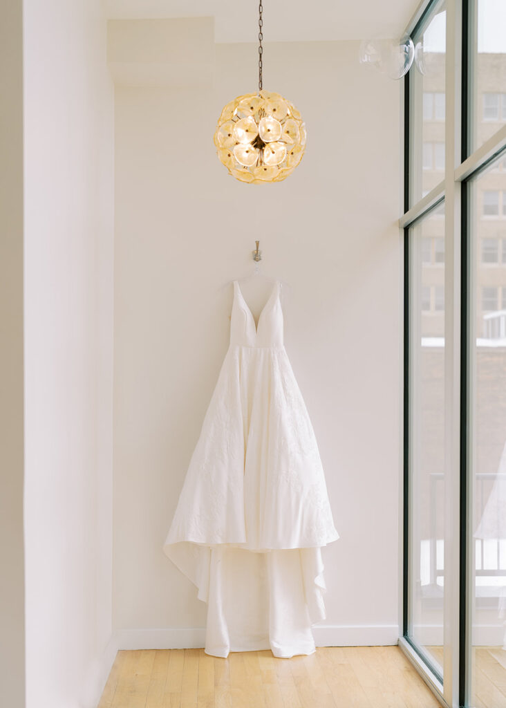 Bridal gown displayed in front of large windows with soft natural light at The Glass Box