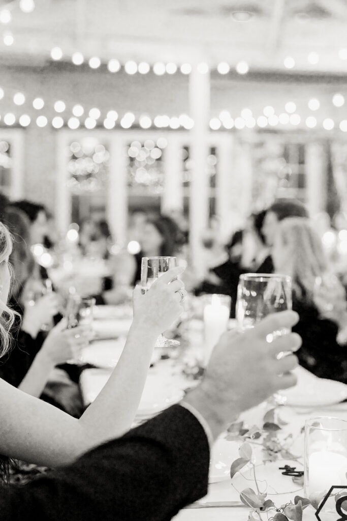 Wedding guests raising glasses during toasts at the reception