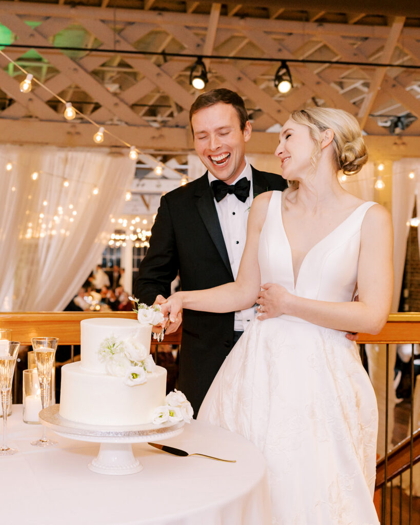 Bride and groom laughing and celebrating after cutting their wedding cake