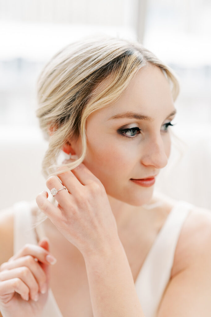 Bride in natural light applying final touches before the wedding
