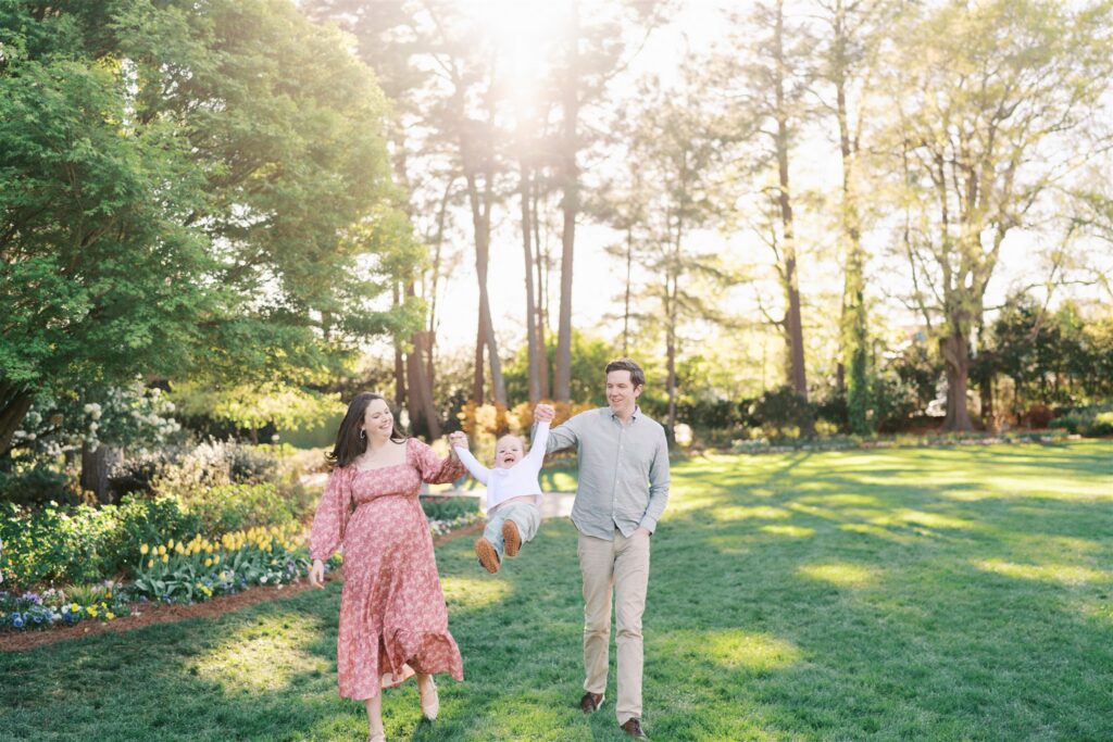 Toddler swinging through the air with joy during golden hour at WRAL Azalea Gardens Raleigh NC