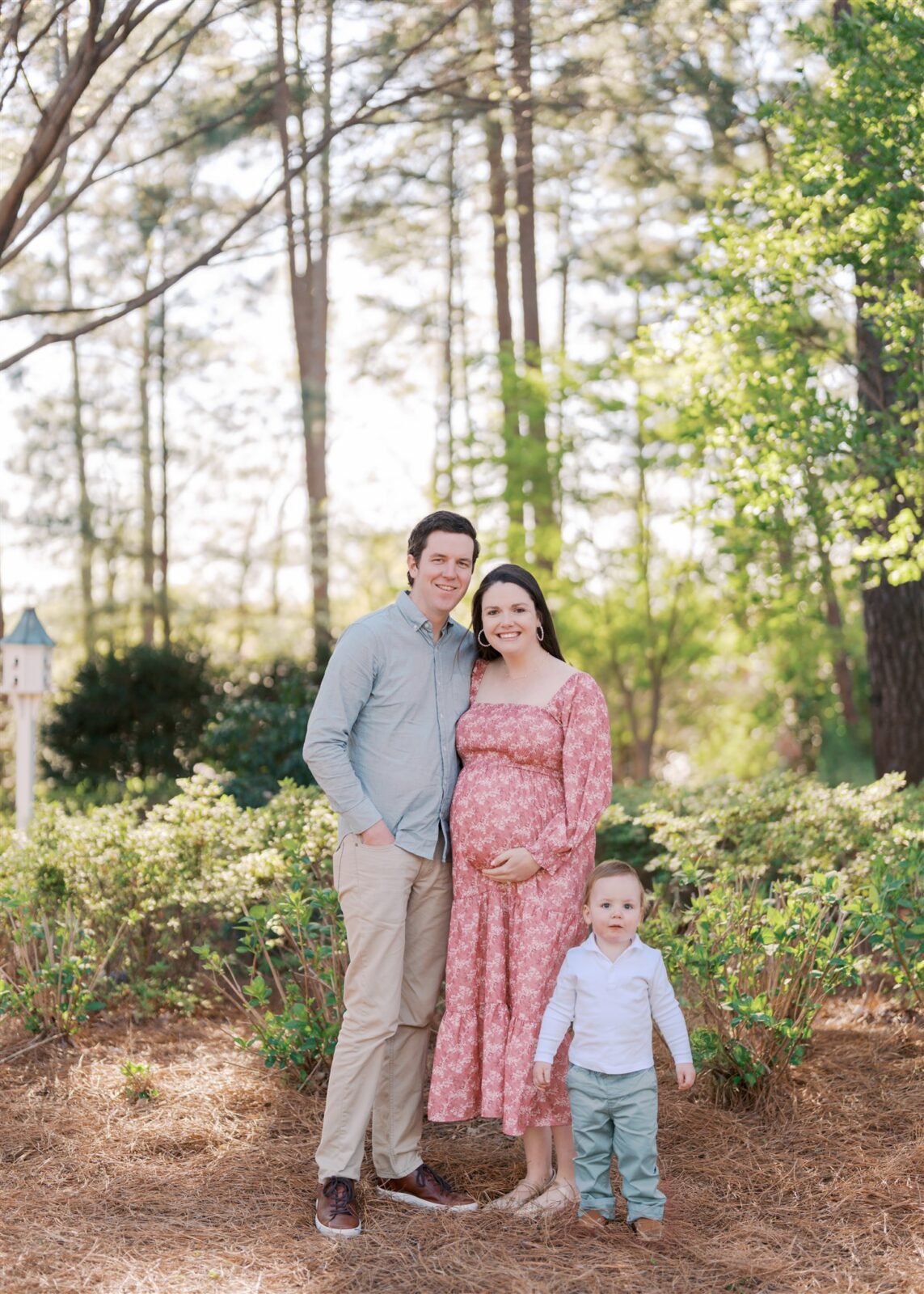 Smiling family posing together for maternity photos at WRAL Azalea Gardens in Raleigh NC