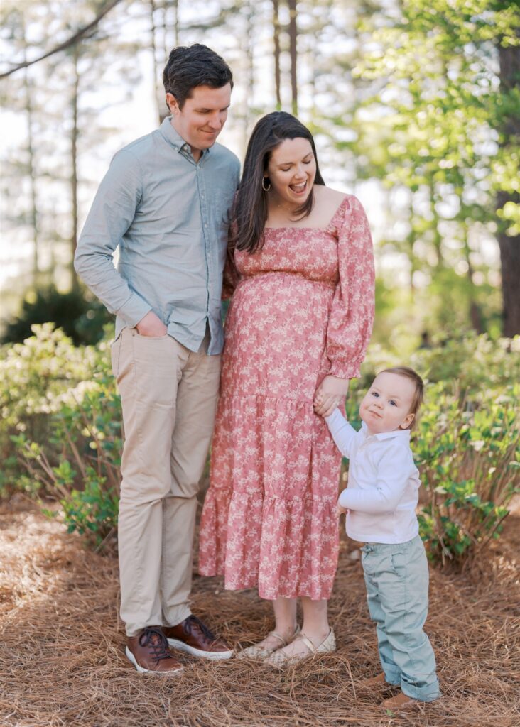 Toddler reaching for mom's attention during family maternity session at WRAL Azalea Gardens Raleigh NC