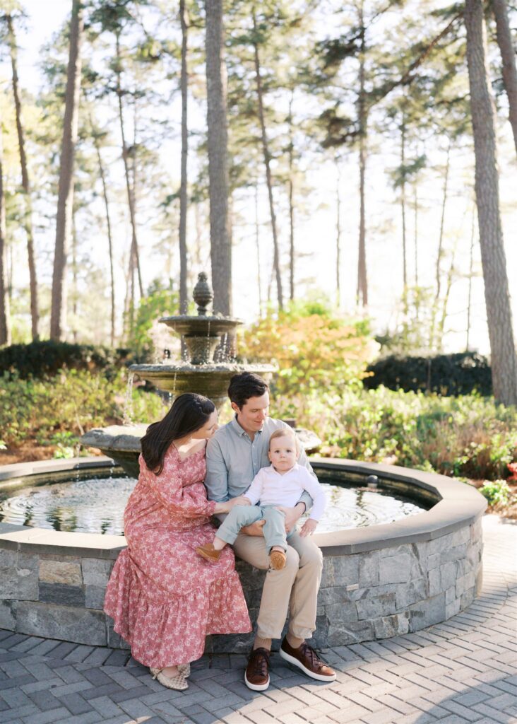 Expecting family together at the fountain at WRAL Azalea Gardens Raleigh NC during spring maternity session