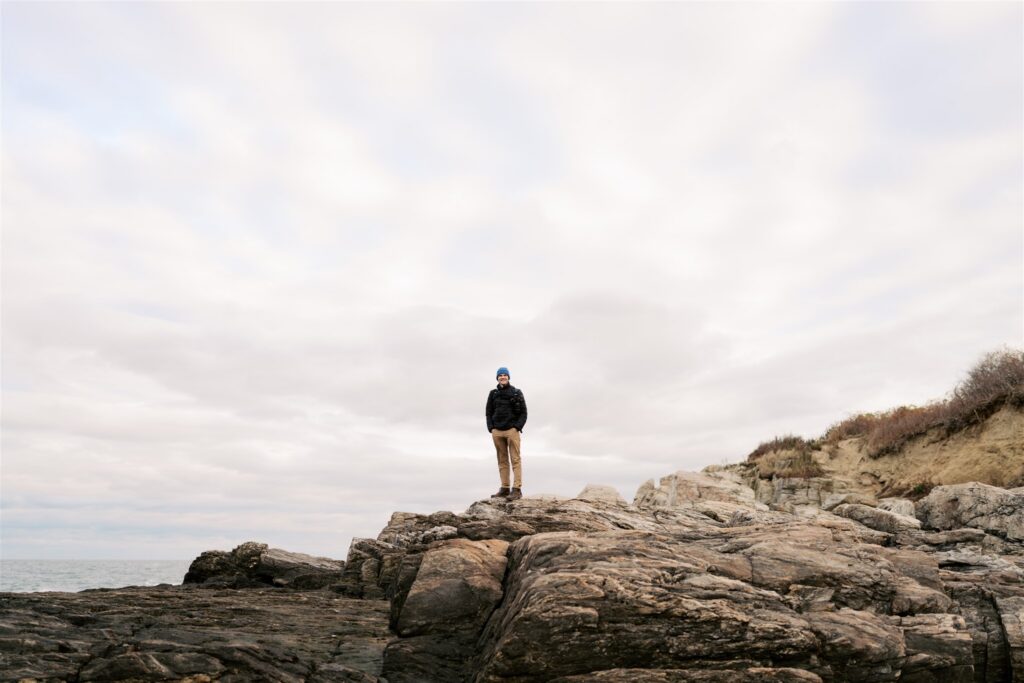 person bundled up against the cold in front of Portland Head Light lighthouse in Cape Elizabeth Maine