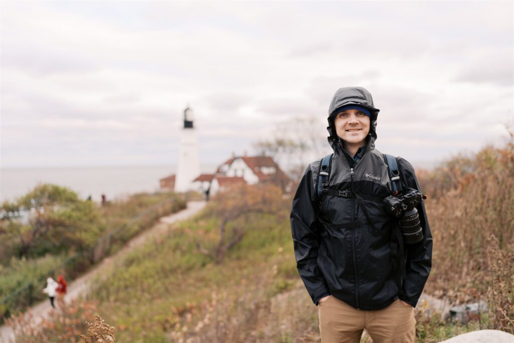 Levi taking in the rocky Maine coastline at Portland Head Light — cold, windy, and completely worth it