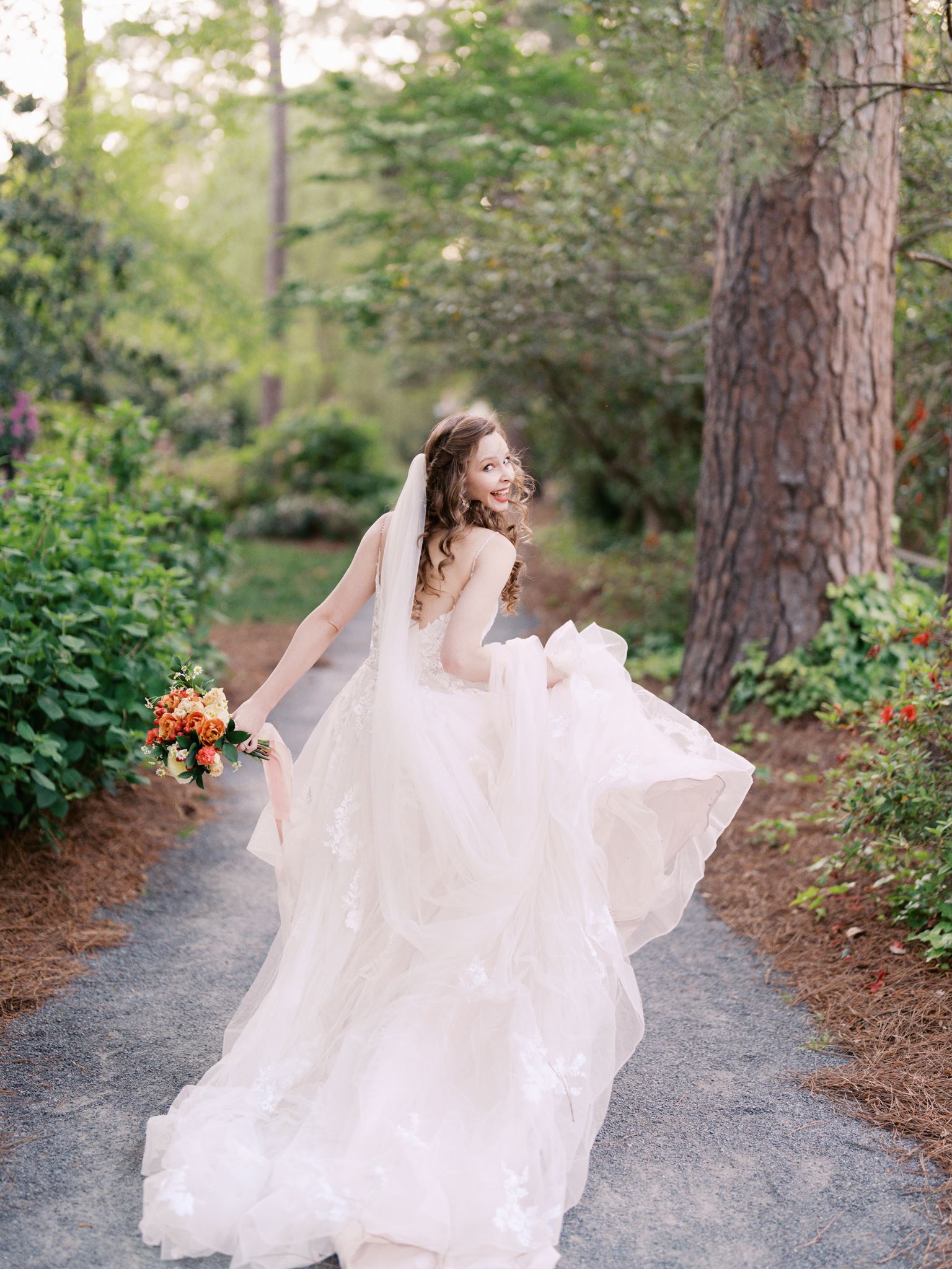 Bride running down a garden path with flowing dress movement during a Glencairn Garden bridal portrait session