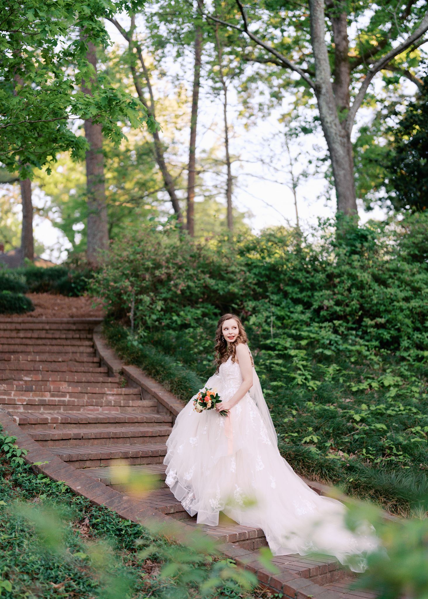 Bride walking up stone steps along a garden path during a Glencairn Garden bridal portrait session in Rock Hill, SC