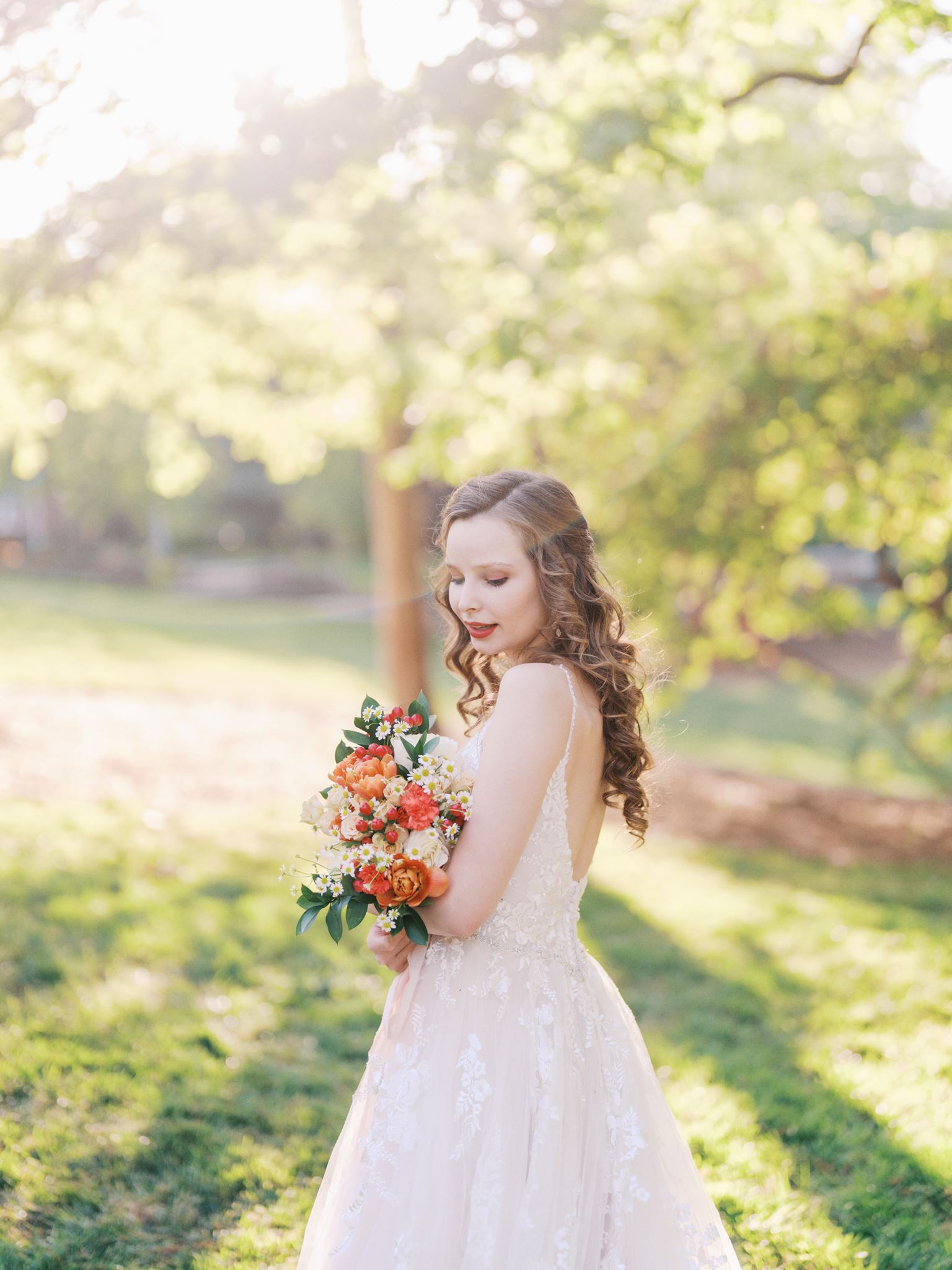 Close-up of bride turning over her shoulder in a sunlit garden with dreamy light and greenery