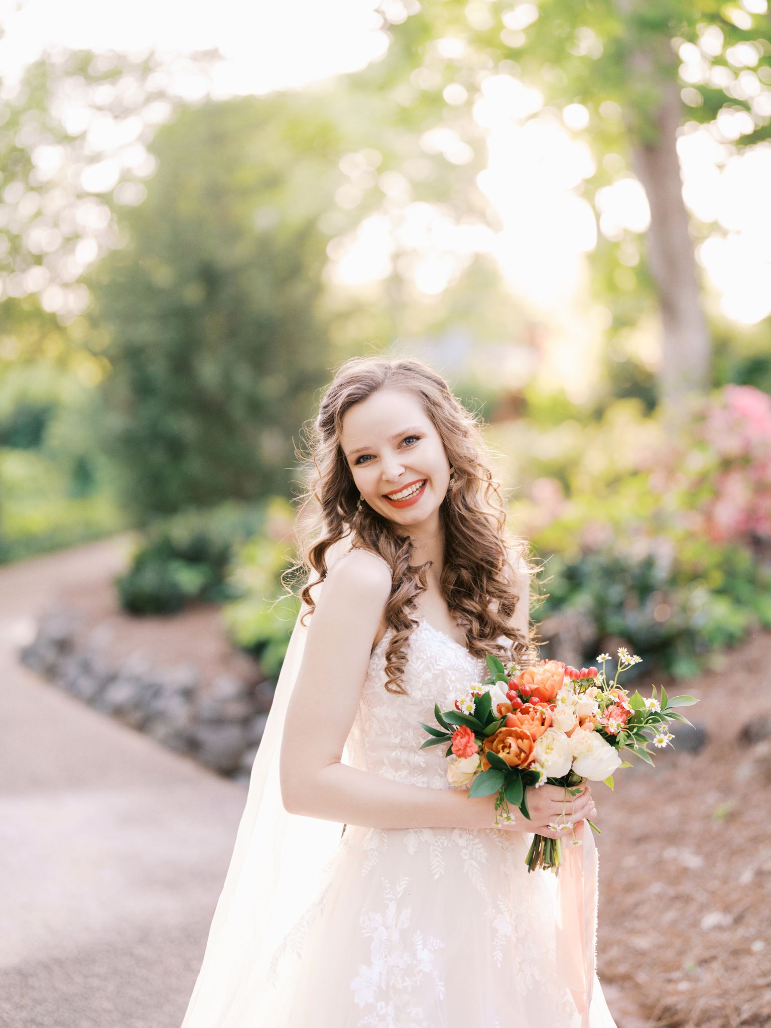 Bride enjoying her bridal portrait session with a natural smile among blooming flowers at Glencairn Garden