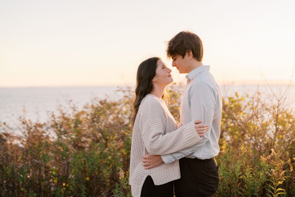 Romantic embrace overlooking the Atlantic Ocean during a sunrise engagement session in Cape Elizabeth, Maine