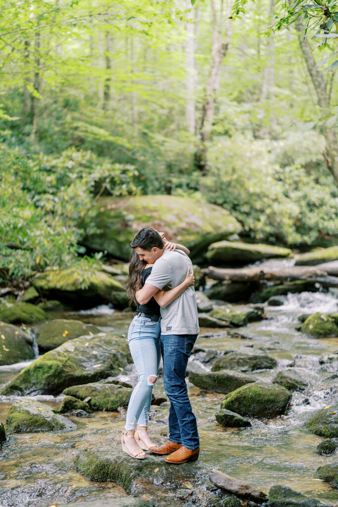 Engaged couple embracing and kissing in the middle of the creek at their Blue Ridge Parkway engagement session near Boone, NC